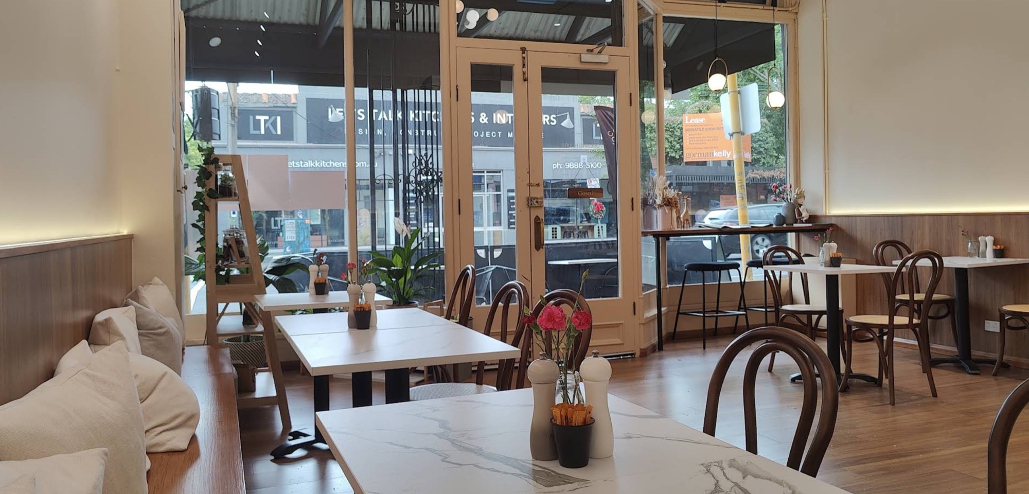 Inside Calla & Cups: dining area with bentwood chairs, marble-topped tables, and a sunlit shopfront onto Canterbury Road