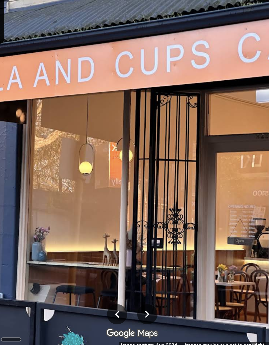 The peach Calla and Cups Cafe shopfront with wrought-iron gate