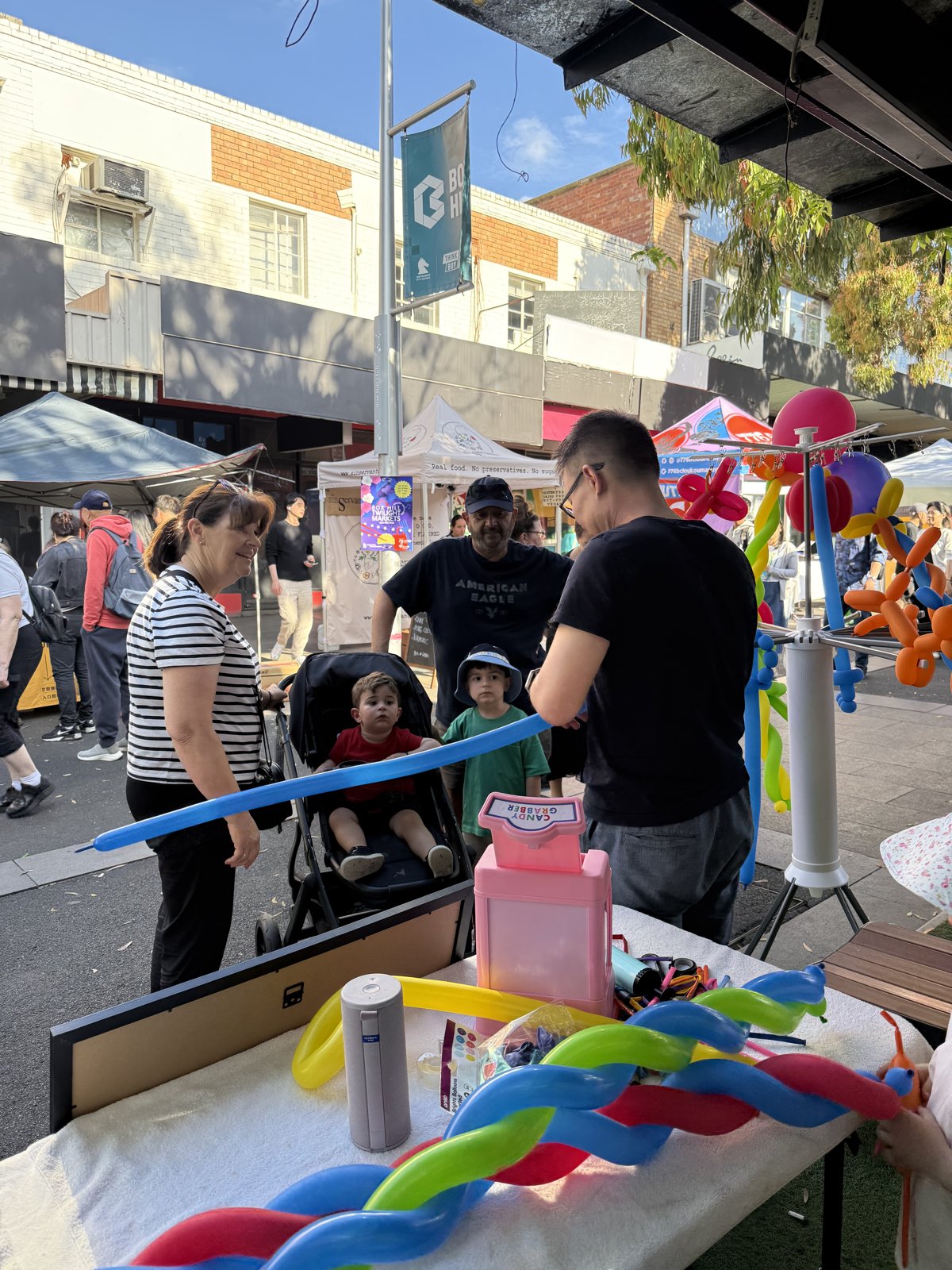 Three generations at the stall — grandparents, strollers and all. Box Hill Twilight Markets.